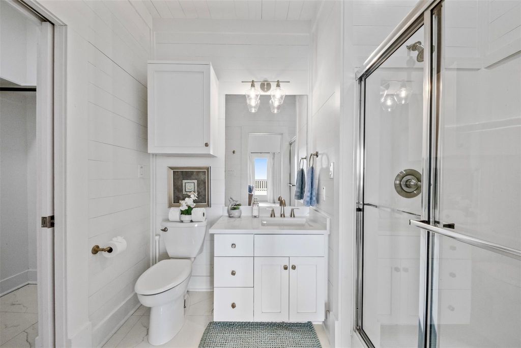 Guest bathroom with glass shower enclosure and shiplap walls