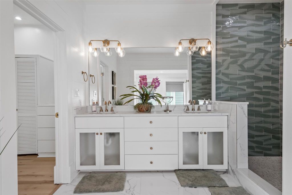 Double vanity with quartz countertop, brass fixtures and glass tile surround, completed by Building Edge Construction