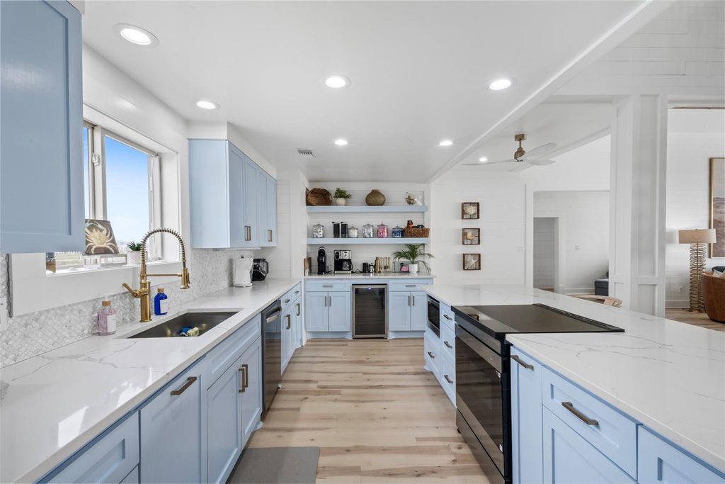 Kitchen run with brass faucet, tile backsplash and open shelving