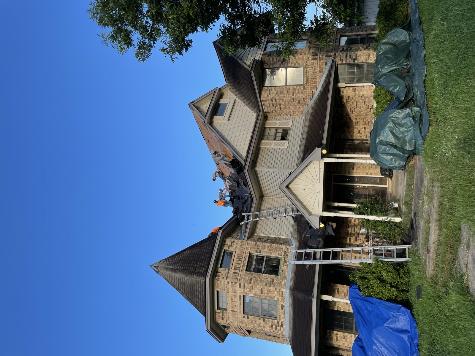 Crew replacing the roof on a large brick home