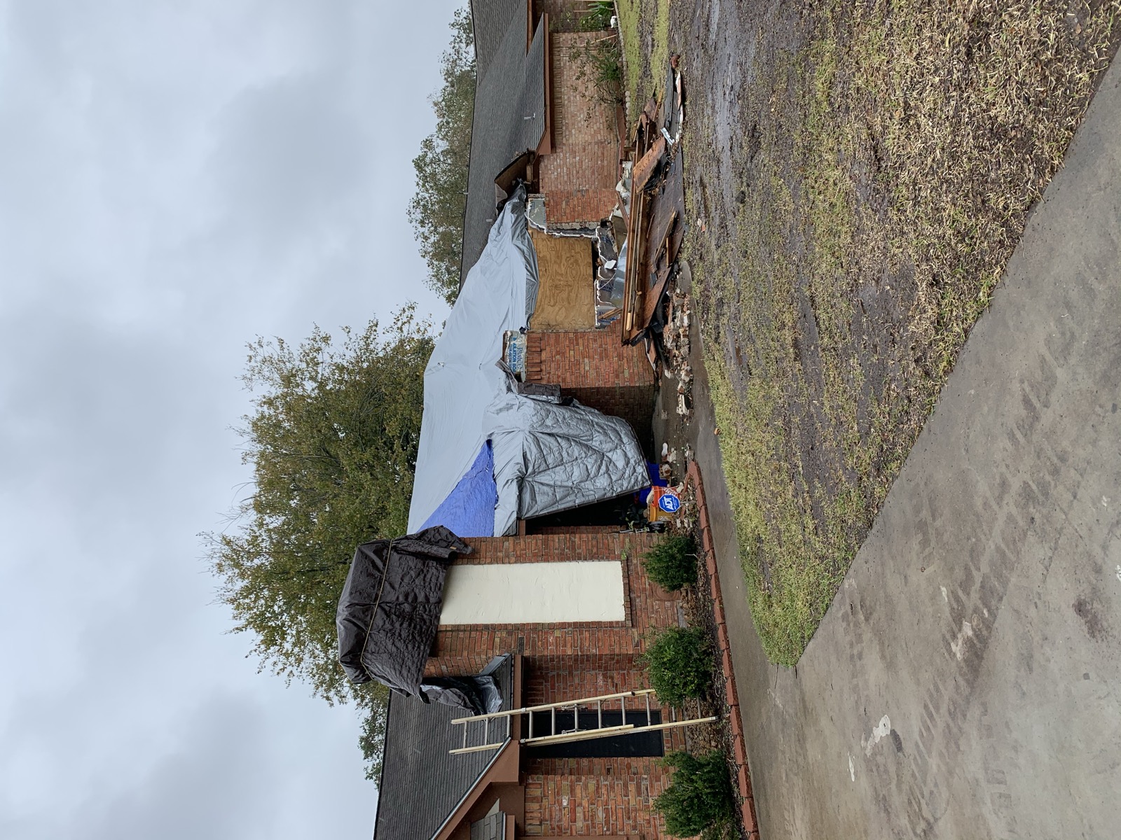 Storm-damaged roof under emergency tarp